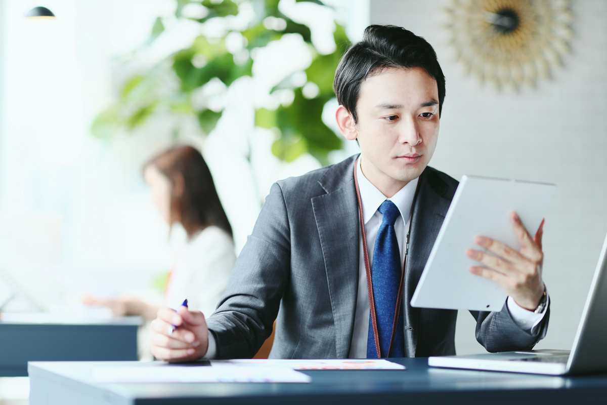 タブレットを見ながら仕事をするビジネスパーソン