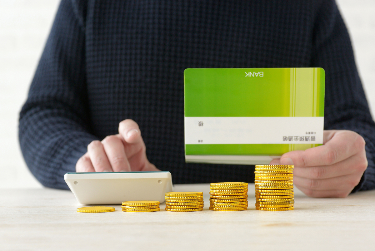 通帳を見ながら電卓を使う男性