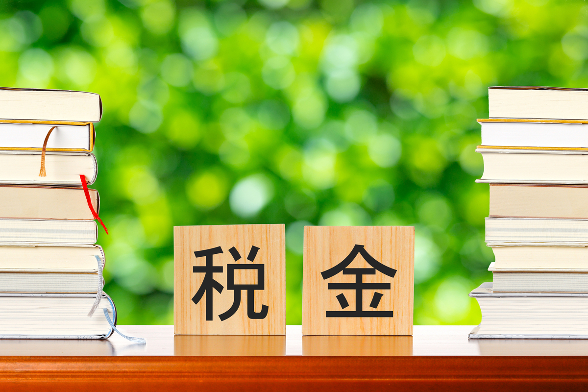 税金と書かれた木のブロックと積み重なった本