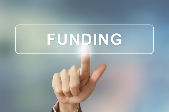 business hand clicking funding button on blurred background