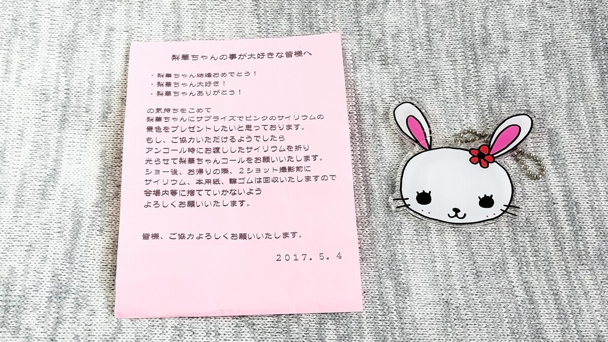 メッセージが書かれたピンク色の紙と、りかうさのアクリルキーホルダーが写っている