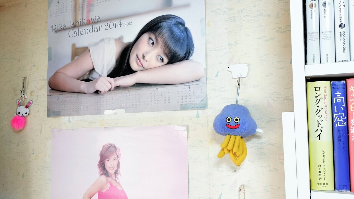 石川梨華ちゃんのガチ恋オタクの部屋の壁の写真。梨華ちゃんのポスター2枚の右側に、ホイミスライムのぬいぐるみが吊り下げられている
