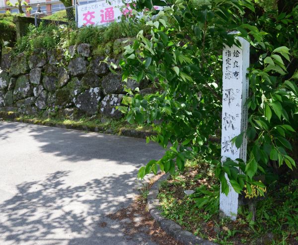 「平松城跡」の標柱、小学校の塀には石垣も確認できる