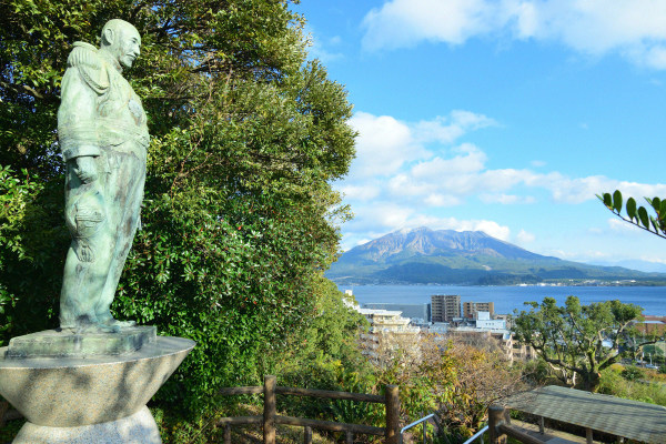 銅像が立つ、海と桜島も見える