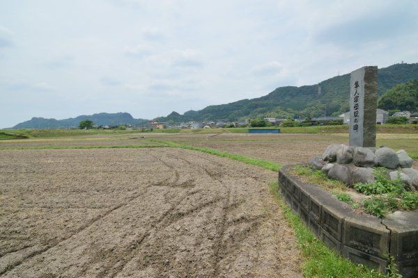 田園地帯に立つ記念碑、遠くの山々は隼人の城跡