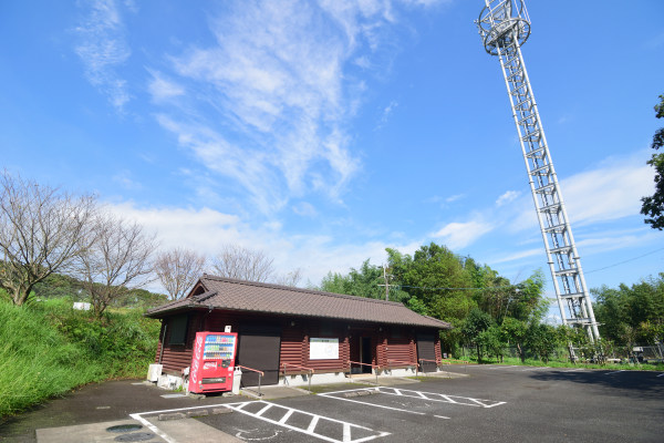 青空の下に鉄塔と公衆トイレ