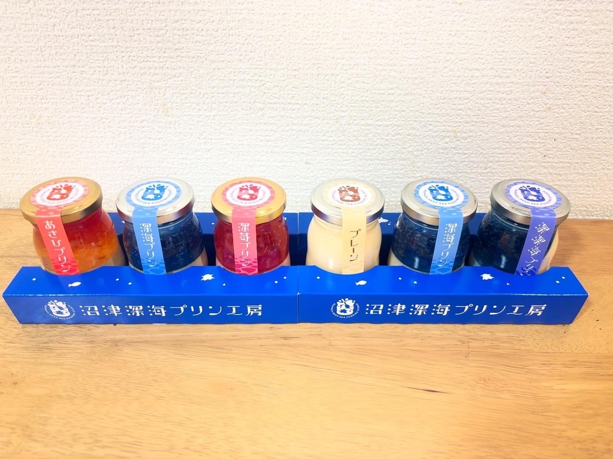 色とりどりのプリン（オレンジ、青、赤、白）が並んでいる。