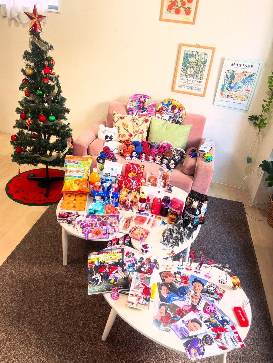 ブンブンジャーのグッズと、カラフルな食べ物が大量に並び、奥にはクリスマスツリーが置かれている
