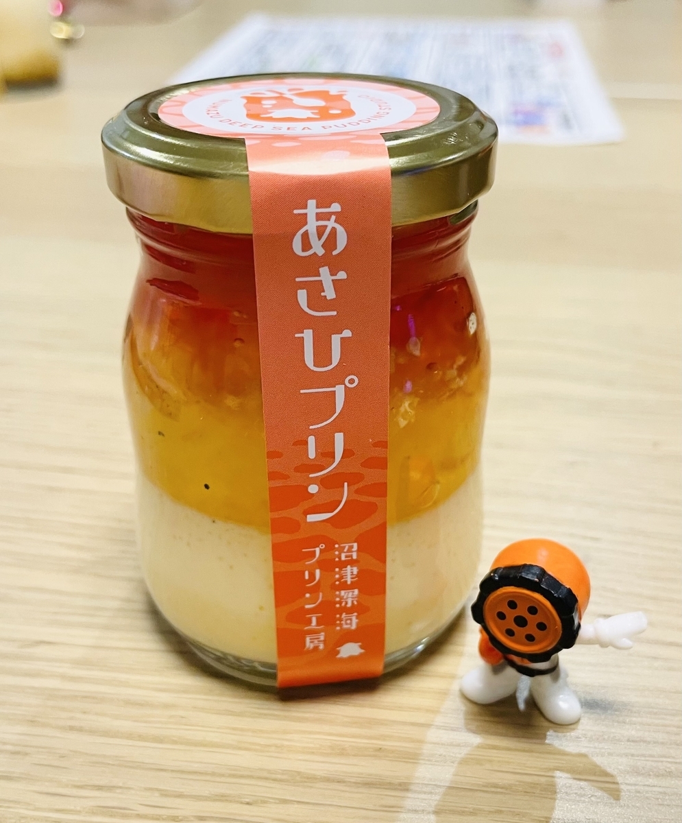 ビンに入ったプリン（オレンジ色のゼリーがのっている）と、手前にブンオレンジの小さいフィギュア