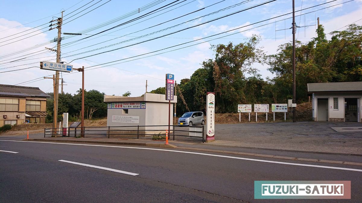 鹿児島県桜島にある黒神中学校前から黒神埋没鳥居へ向かう道中。退避壕とその看板、道向かいに広い砂利の駐車場と男女別のトイレがあるのが分かる。