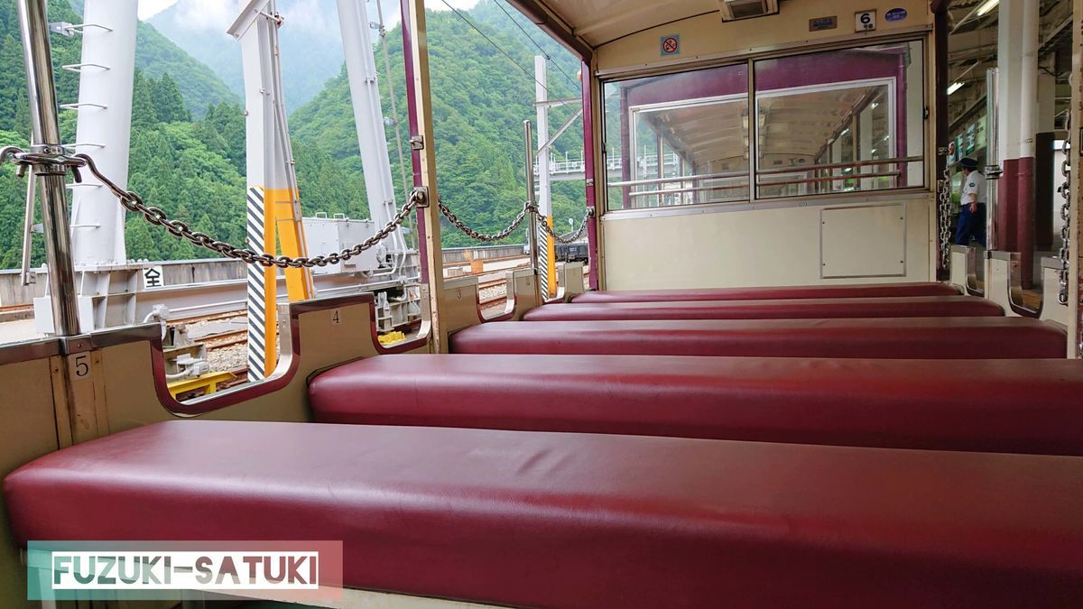 黒部峡谷鉄道のトロッコ電車、普通客車の座席の様子。4人掛けの長椅子が並べられているだけの簡易的な造り。屋根はあるが窓はない。