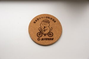「電車屋なのに自転車操業」と書かれたコルク装飾。イラストは自転車に乗る猫
