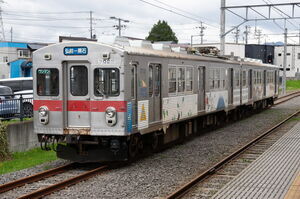 弘前駅留置線に停車中の弘南鉄道7000系(7012編成)。前面は赤帯で、側面は大学のラッピングをしたデザイン