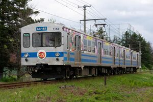運動公園前駅付近の直線区間を走行する、弘南鉄道7000系(7102編成・柏木農業高校100周年HM&ラッピング)