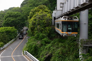 トンネルを抜けて山から出てくる湘南モノレール5000系