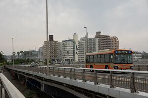 曇り空の下、江ノ島大橋を渡る江ノ電バス159号車。オレンジ色のバス