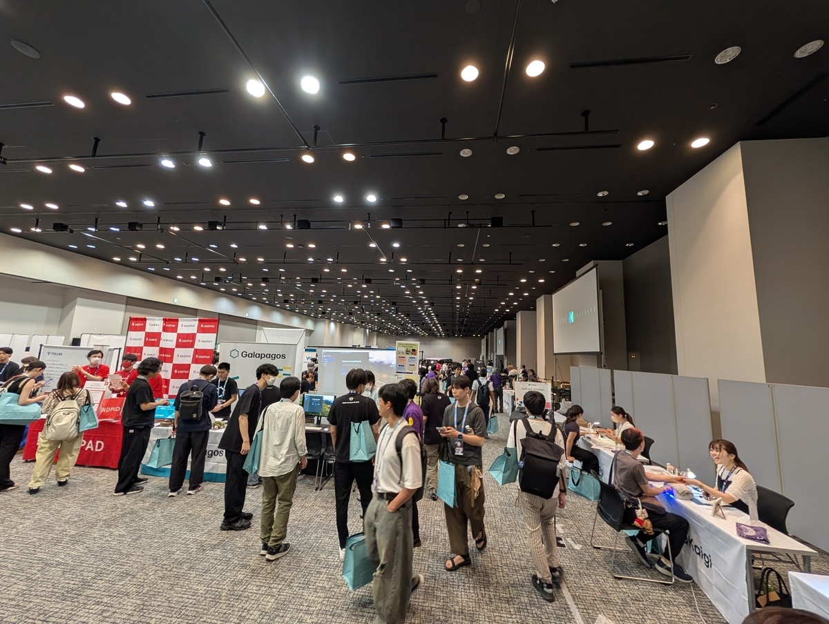 ホール内で、ブースが並ぶなかを参加者が歩いている