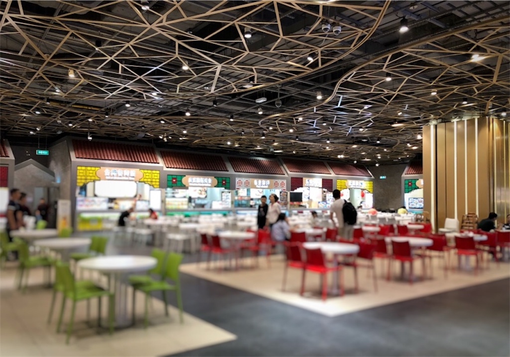 様々な飲食店とテーブルや椅子が並ぶフードコート内