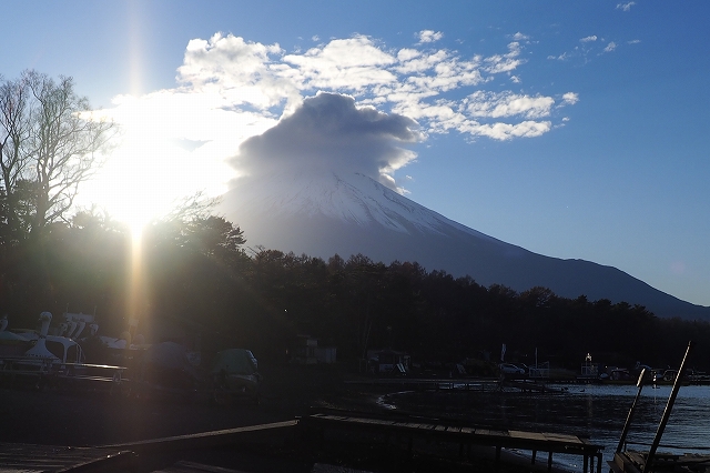 富士山の頂上に雲がかかり、太陽は左にそれています。