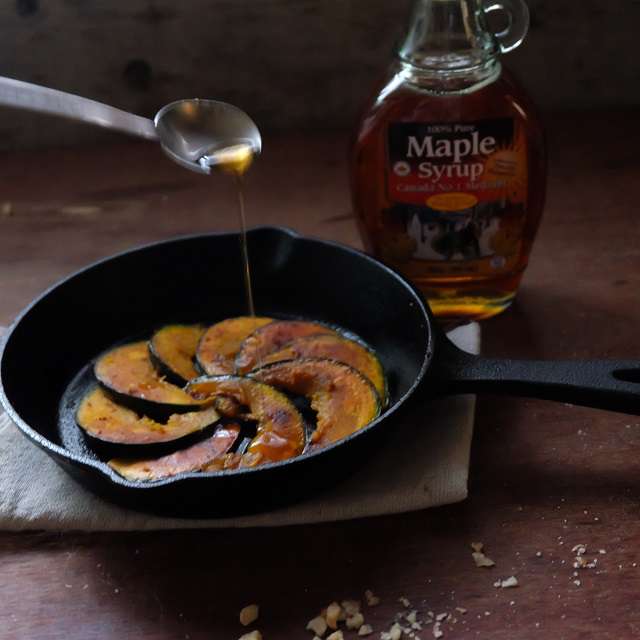 かぼちゃを裏返してスキレットに並べたら、メープルシロップをかけてるところ
