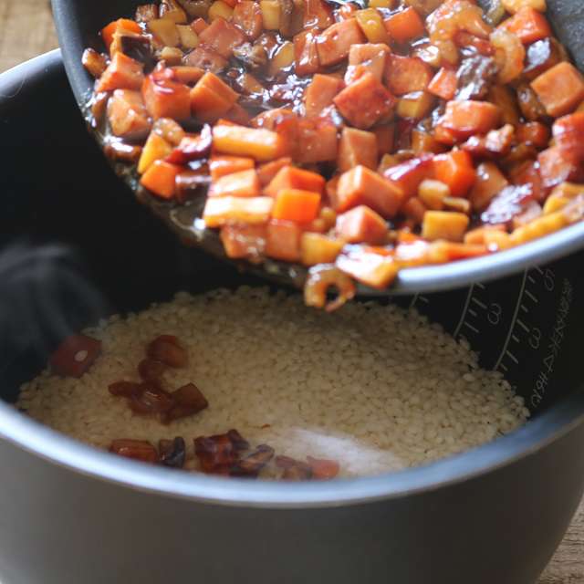 炒めた具とフライパンに残った汁を炊飯器に加え、スイッチをを入れる