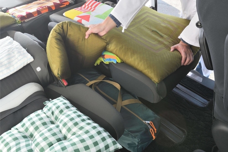 ステップワゴン スパーダの２列目のキャプテンシートの間にうまれる隙間をバックと座布団を使って埋めている写真