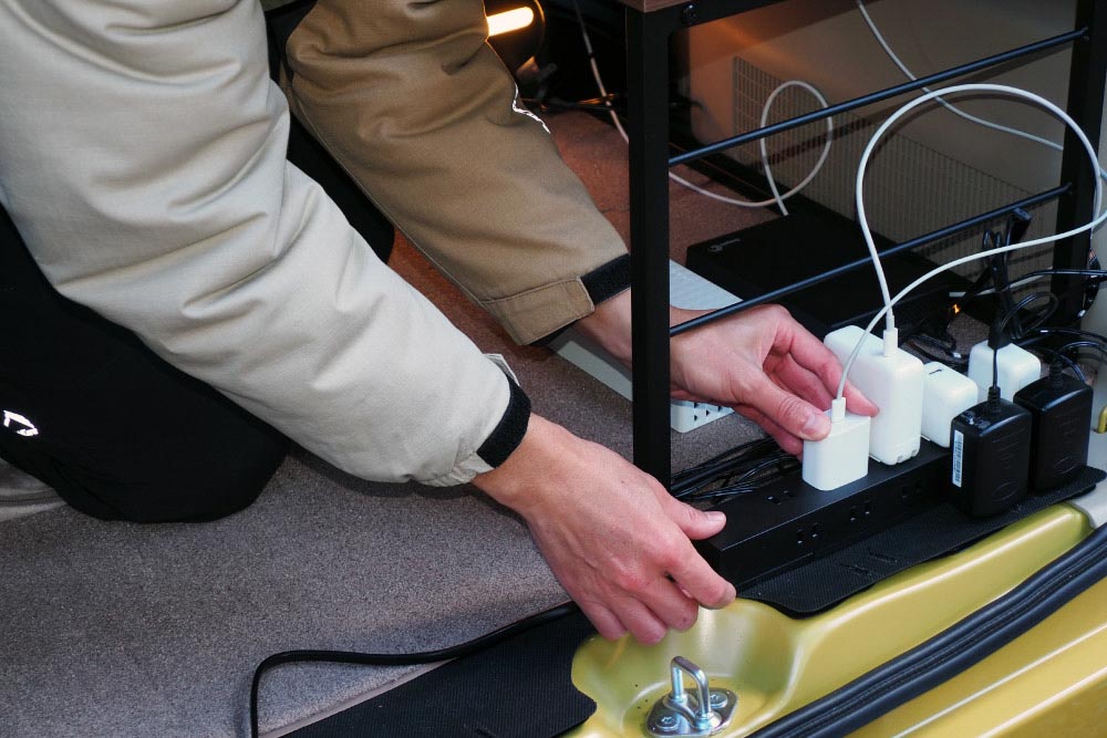 電源タップのコンセントに充電器を指す小川さん