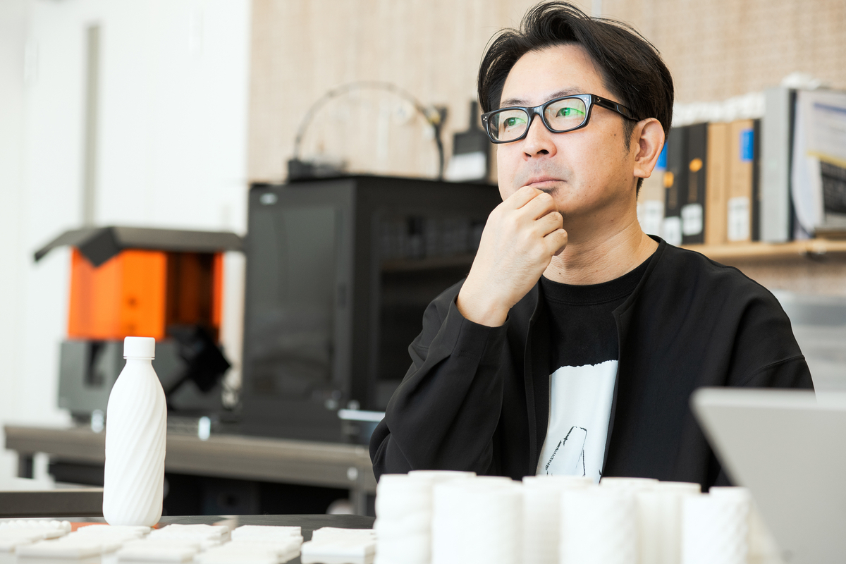 3Dプリンターで作ったプロトタイプが並び、プロダクトデザインチームの内田が話している様子