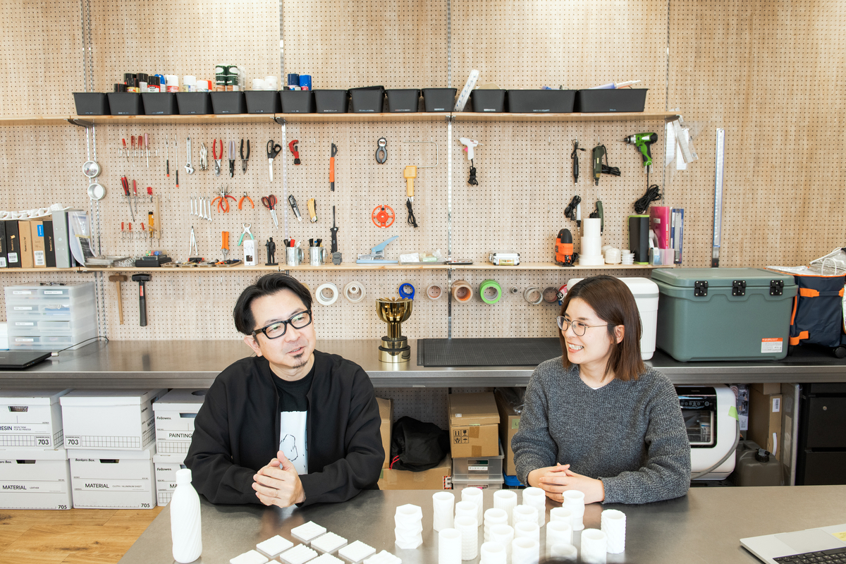 3Dプリンターで作ったプロトタイプが並び、プロダクトデザインチームの内田と橋本が話している様子