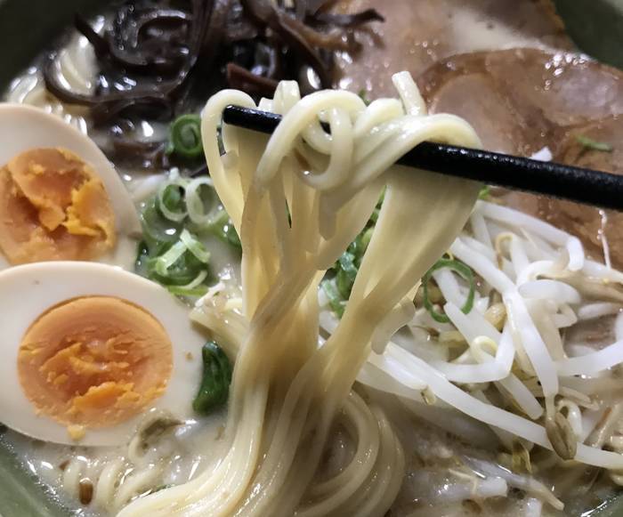 鹿児島黒豚とんこつらーめんの麺を持ち上げている