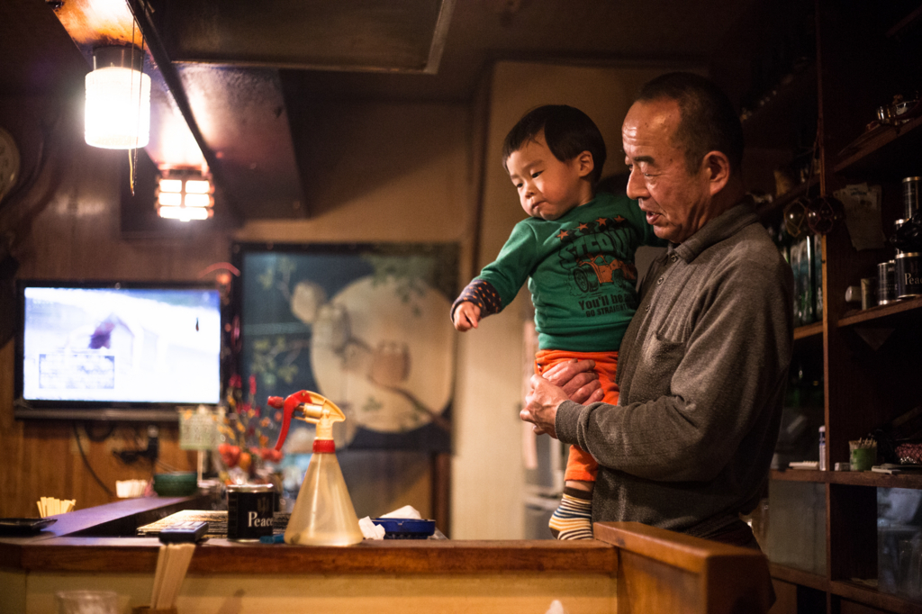 焼き鳥を焼くマスターに飛びつくたける少年。