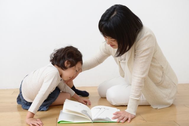 女の子とお母さんが一緒に本を読んでいる画像