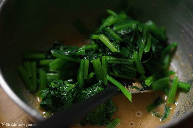 醤油と水で溶いたピーナッツバターのつゆにほうれん草を和える様子