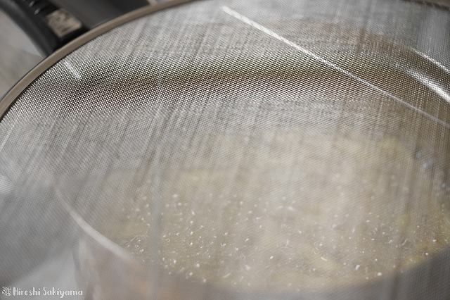 揚げ物に油はね防止網を使っている様子