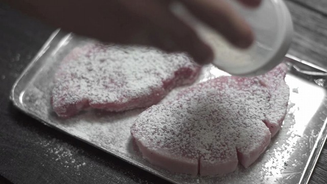 小麦粉ふりふりストッカーを使って豚肉に小麦粉をふりかける様子