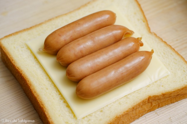食パンにチーズ、その上にウインナーを並べた様子