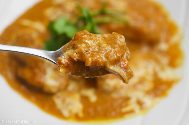 パプリカとトマトのチキンココナッツカレーをスプーンですくった様子