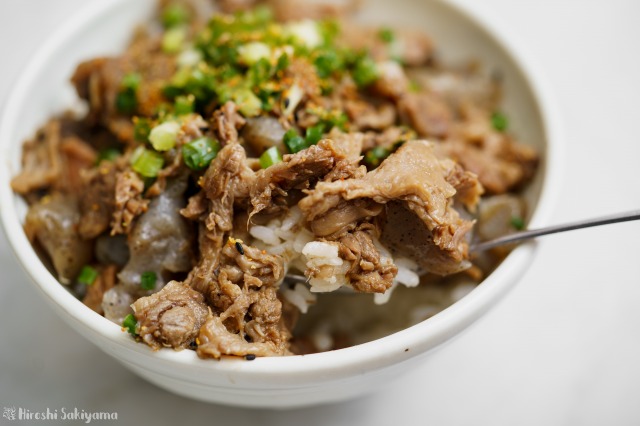 こんにゃくと牛すじの煮込み丼をスプーンですくった様子