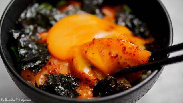 サーモンの辛漬け丼、サーモンに卵黄を絡める