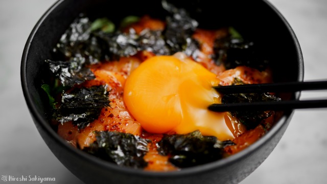 サーモンの辛漬け丼、卵黄を割る