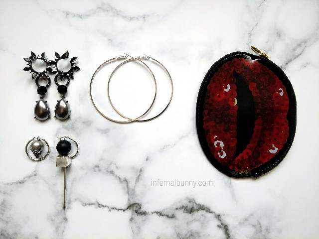 ボリューミーなドロップピアス、ドクロと細いシルバーの棒のアシンメトリーピアス、大きなフープピアス、赤いフラットポーチ。