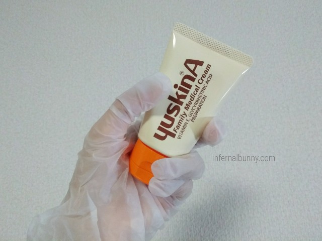 ビニール手袋をはめた手にユースキンのチューブを持っている。