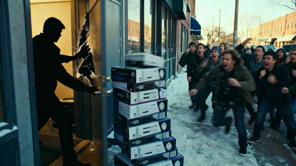 Store backroom door swings open to stacked console boxes as a crowd charges in—explosive adrenaline, chaotic desperation, and pure restock frenzy on a snowy street