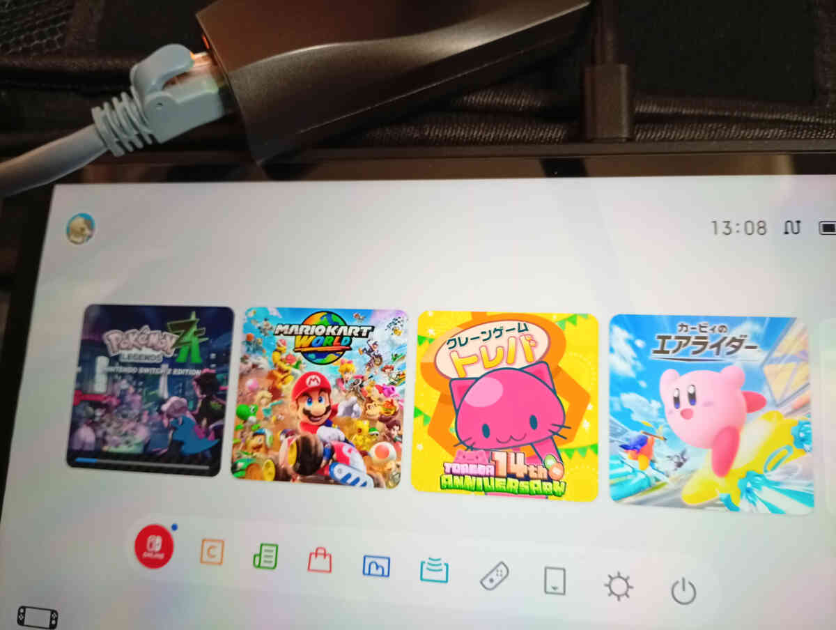 Close-up of a Switch2 home screen with a wired LAN adapter plugged in—raw “no more lag” relief, rock-solid connection vibes, locked-in focus before the next online match, calm after chaos