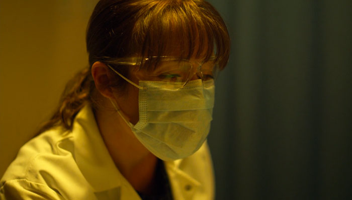 映画『コンテイジョン』で、女性医師がマスクをして患者を診察する