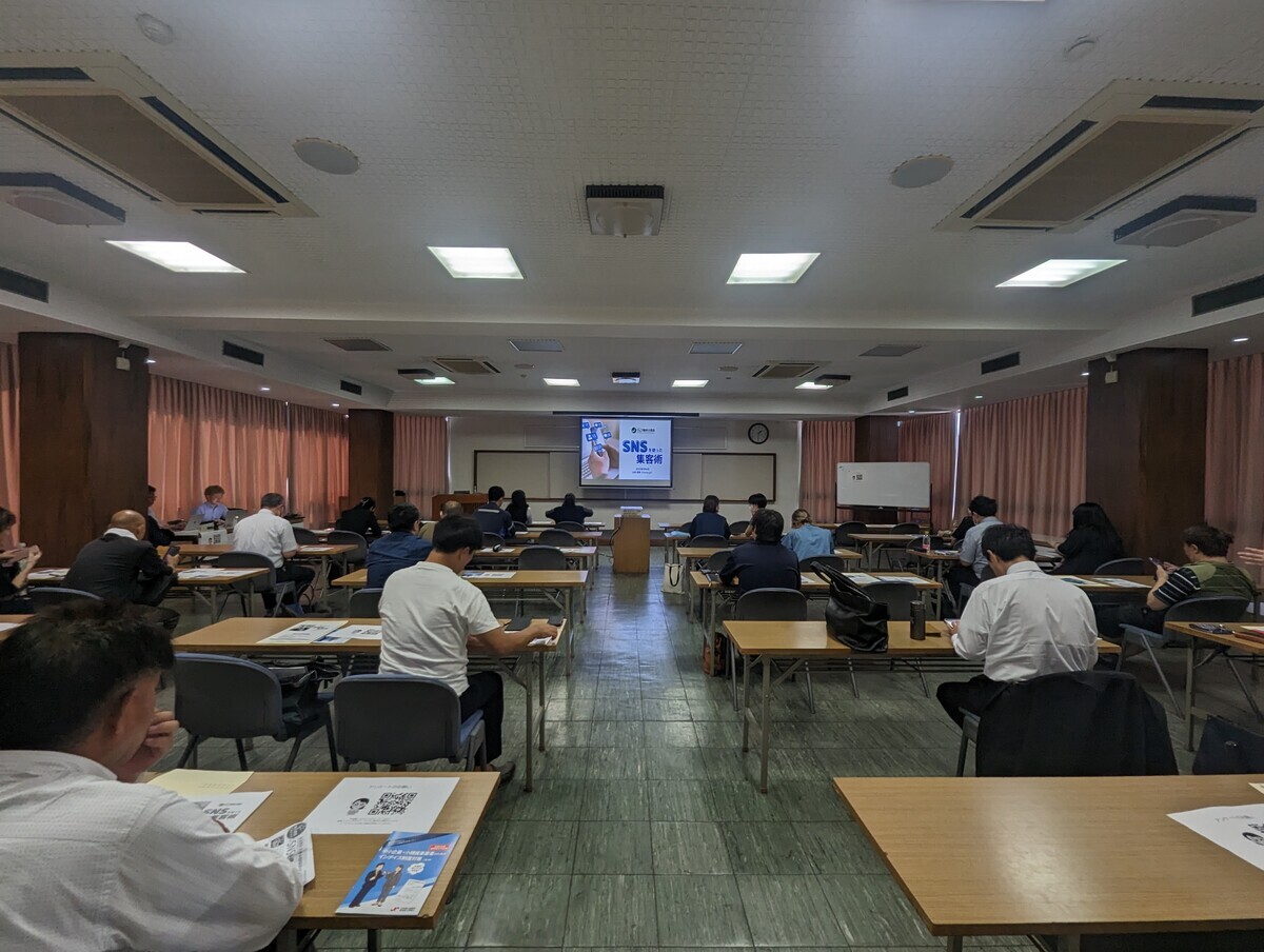 会場の後ろからのショット。正面にはスライドの1枚目のタイトル。