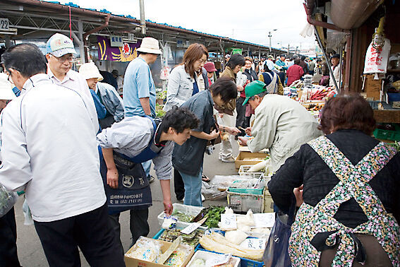 早朝の神子田朝市.季節の野菜や旬の果物などの商品が並び、活気ある様子。