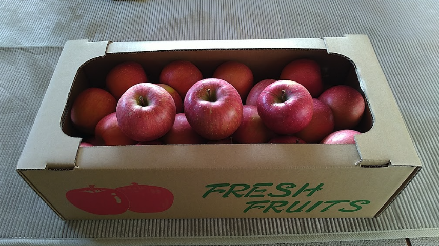 立派なサンふじ中玉1箱とその上がおまけにいただいた大玉サンふじ3個。