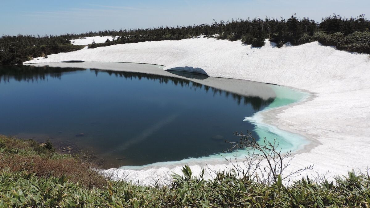 八幡平ガマ沼の残雪と水面、水際にハート型の模様が見える