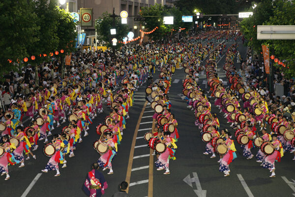 夜の盛岡市中央通で、色とりどりの浴衣姿の踊り手が太鼓を打ち鳴らすさんさ踊りの大群舞